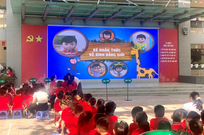 A group of people sitting in a room with a large screen
Description automatically generated with low confidence