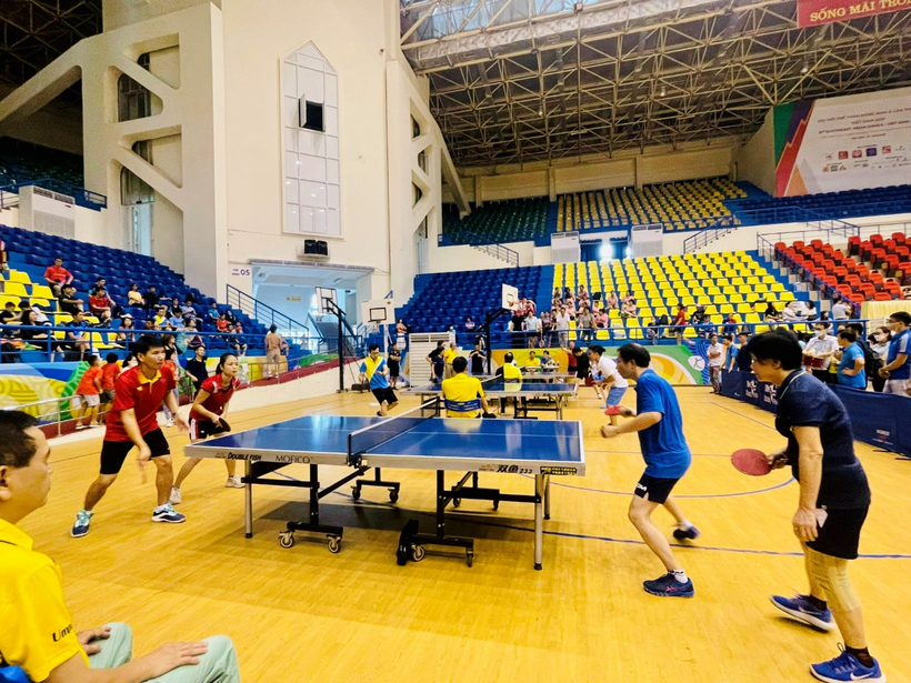 A group of people playing ping pong in a large room
Description automatically generated with medium confidence