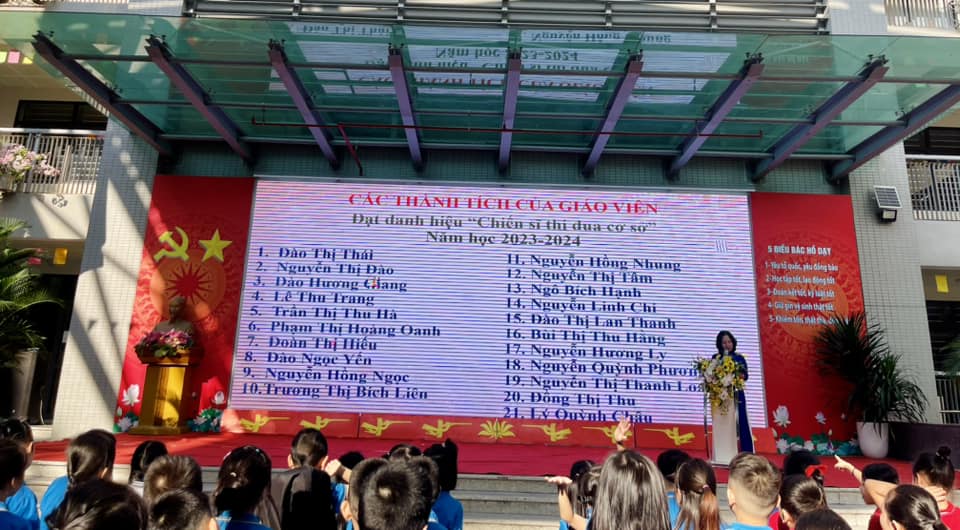 A group of people standing in front of a large screen
Description automatically generated