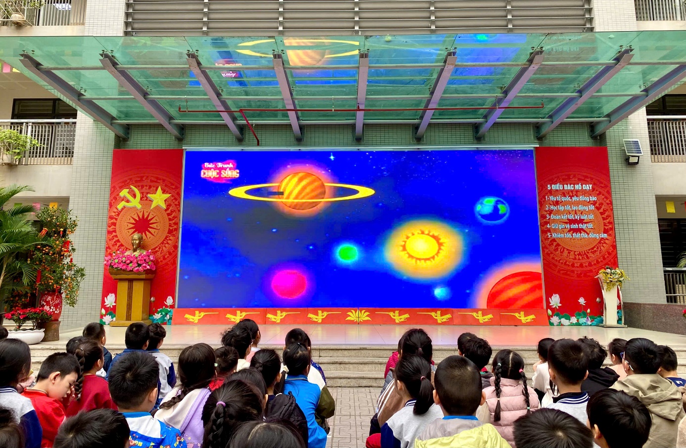 A group of children sitting in front of a large screen
Description automatically generated