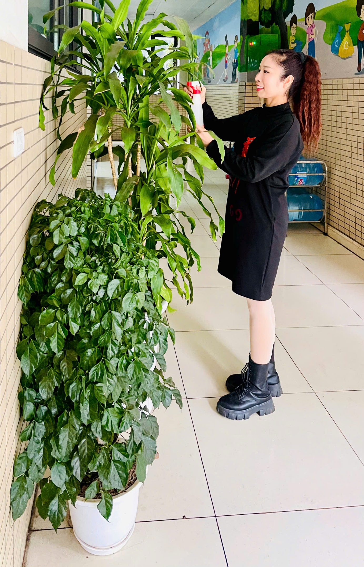 A person in black standing by a plant
Description automatically generated