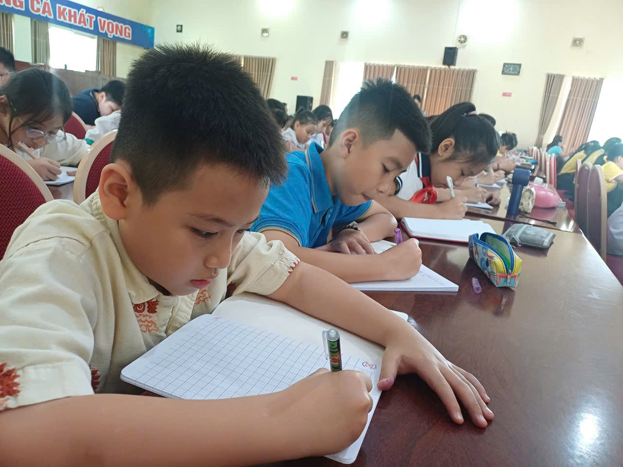 A group of children writing in a classroom
Description automatically generated